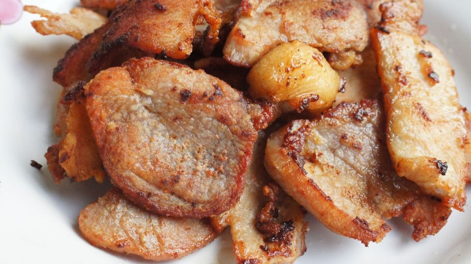 Friendo los trozos de cerdo a fuego lento en una sartén