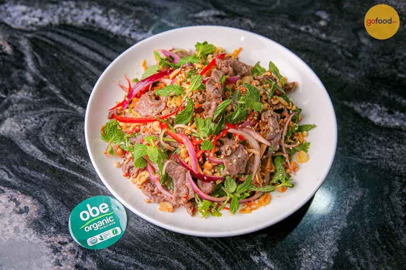 Plated finished Vietnamese Beef Salad (Nộm Bò Bóp Thấu) topped with peanuts and herbs