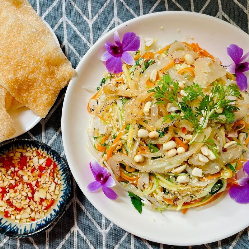 A beautifully presented finished dish of jellyfish and celery salad, garnished with peanuts and herbs, ready to be served.